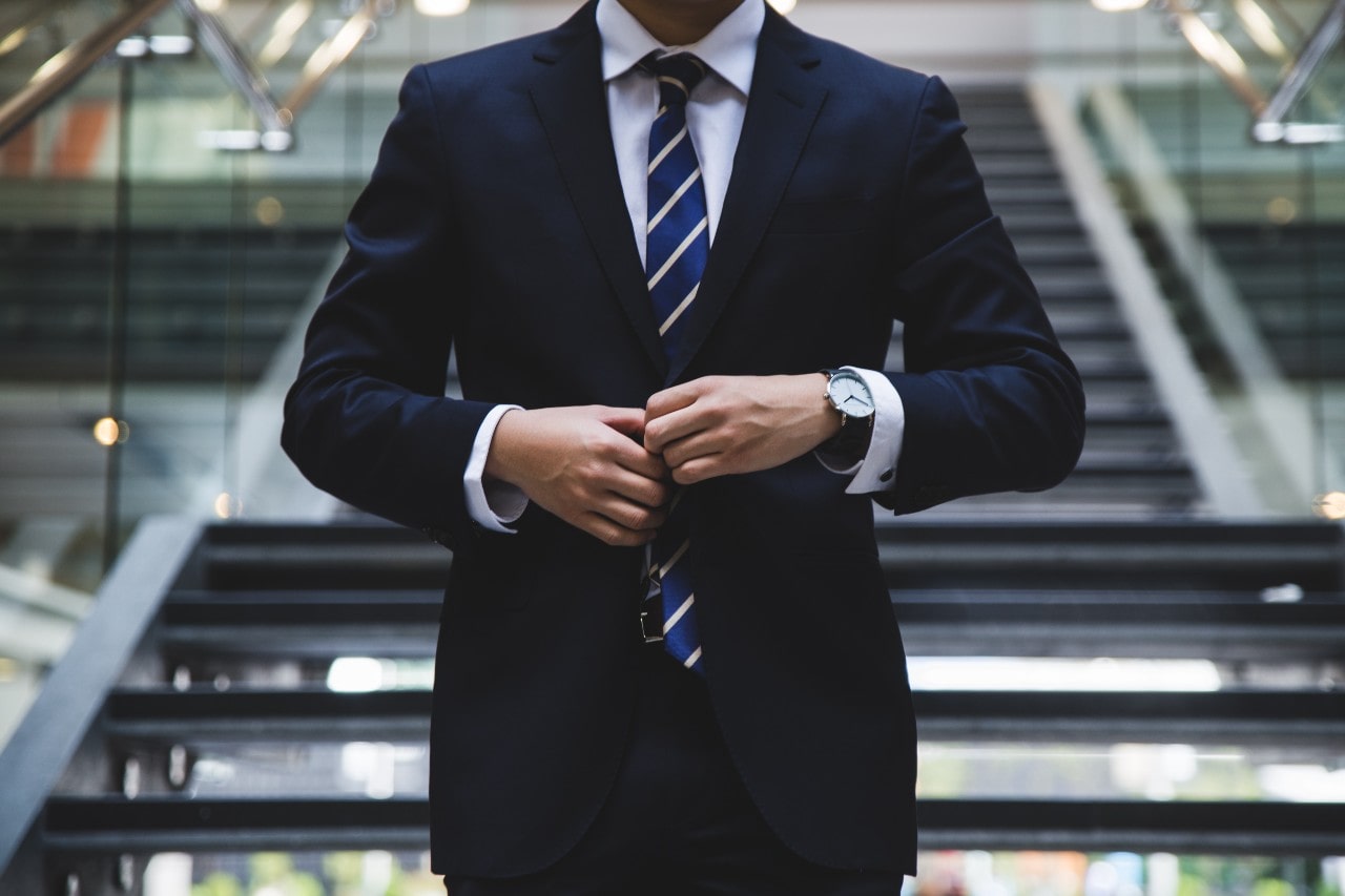 Man walking down the stars in a navy suit and a matching watch