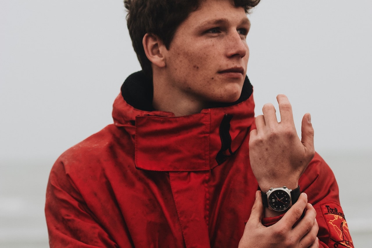 a man in a red raincoat wearing a silver and black watch